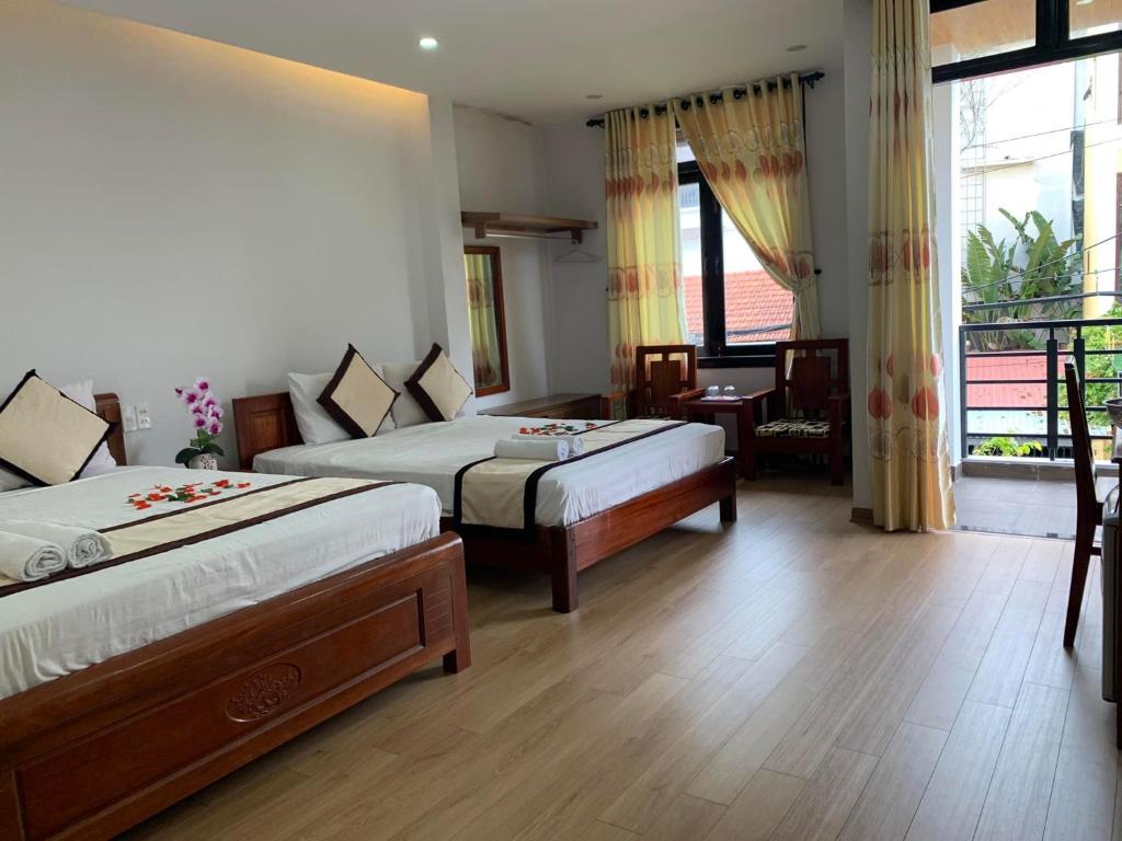 a hotel room with two beds and a balcony at The Sun Homestay in Hoi An