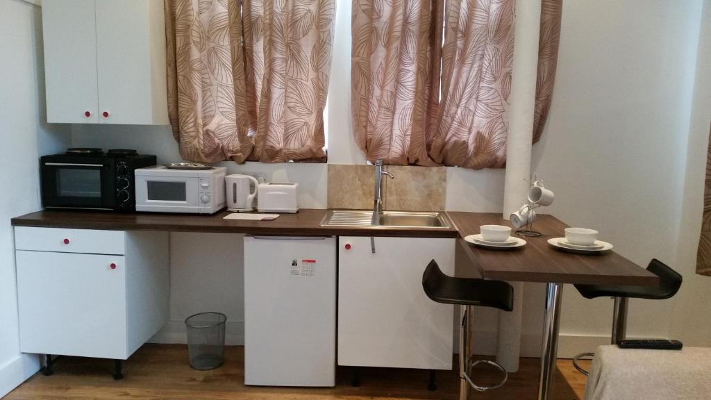 a kitchen with a counter with a microwave and a table at Shepherd's Bush Flats in London