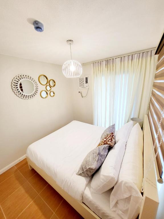 a bedroom with a white bed and a window at Kate's Corner @ One oasis Condo in Cagayan de Oro