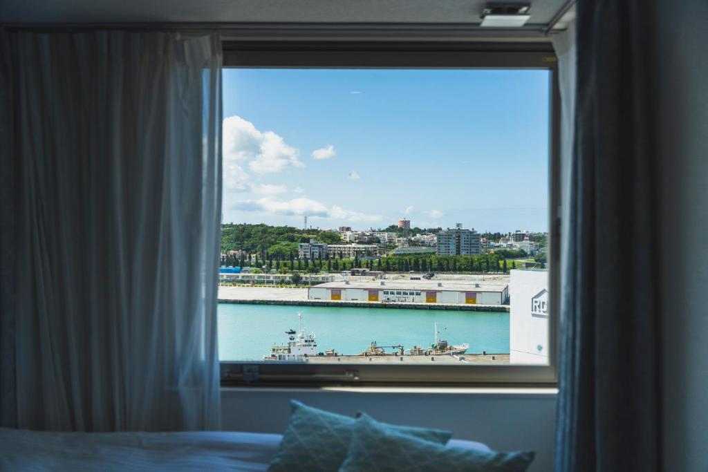 ventana del dormitorio con vistas a un barco en el agua en Rembrandt Style Naha en Naha