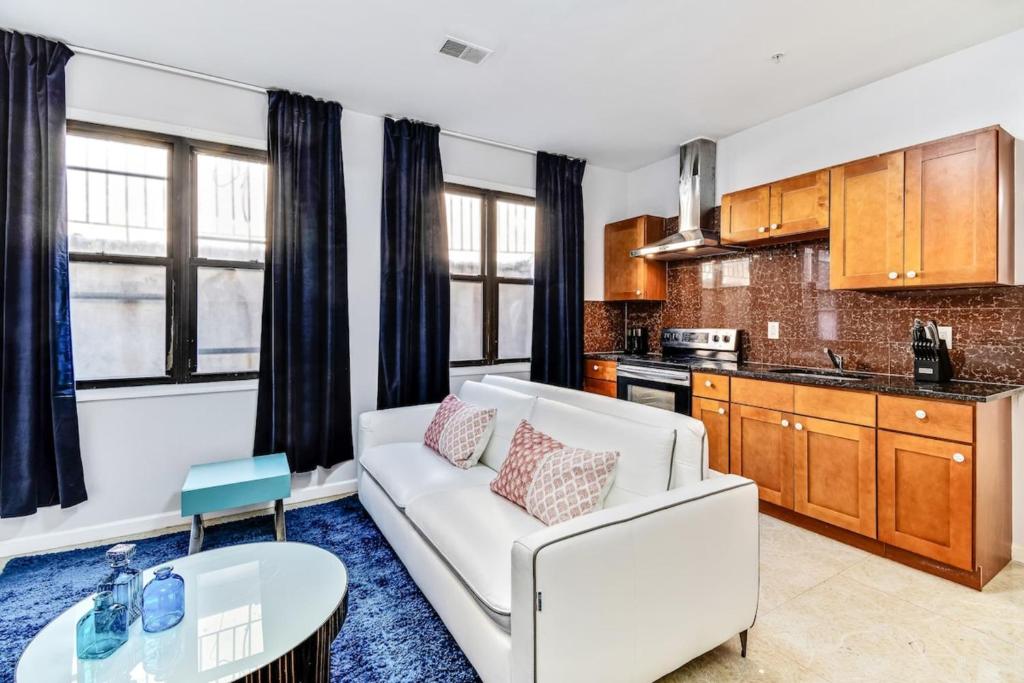 a living room with a white couch and a kitchen at Lovely 2bd Apt steps from the Convention Center in Philadelphia