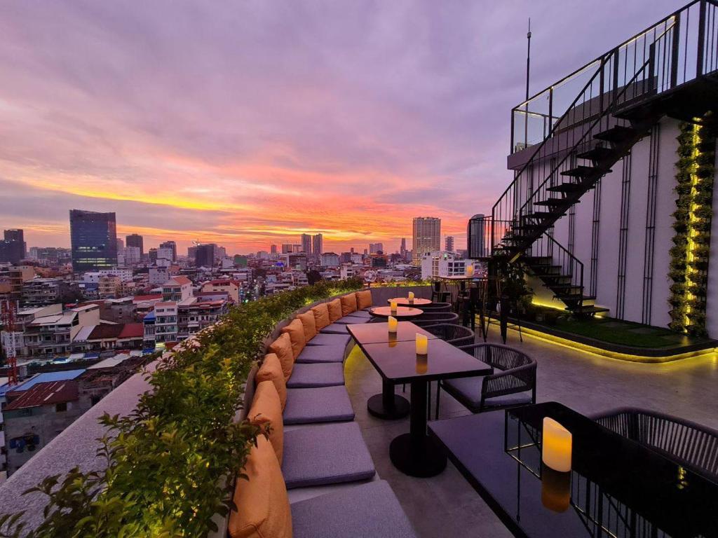 a rooftop patio with tables and a view of a city at Harmony Phnom Penh Hotel in Phnom Penh