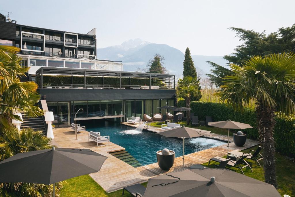 a swimming pool with umbrellas in front of a building at Hotel Gartner in Tirolo