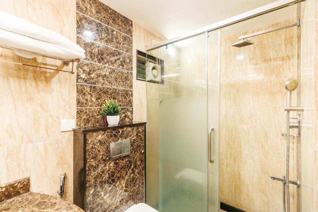 baño con ducha y puerta de cristal en Octave Castle Suites, en Bangalore