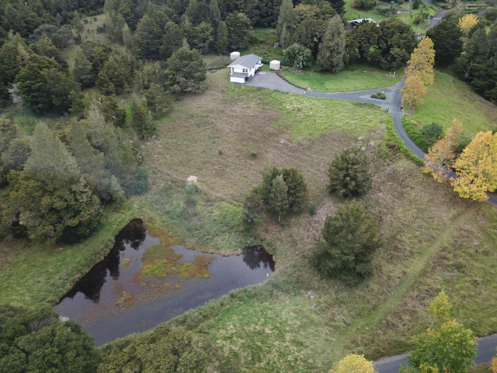 an aerial view of a house on a field with a river at Superior Cottage - St Enoch and St Elijah Monastery in Kaikohe