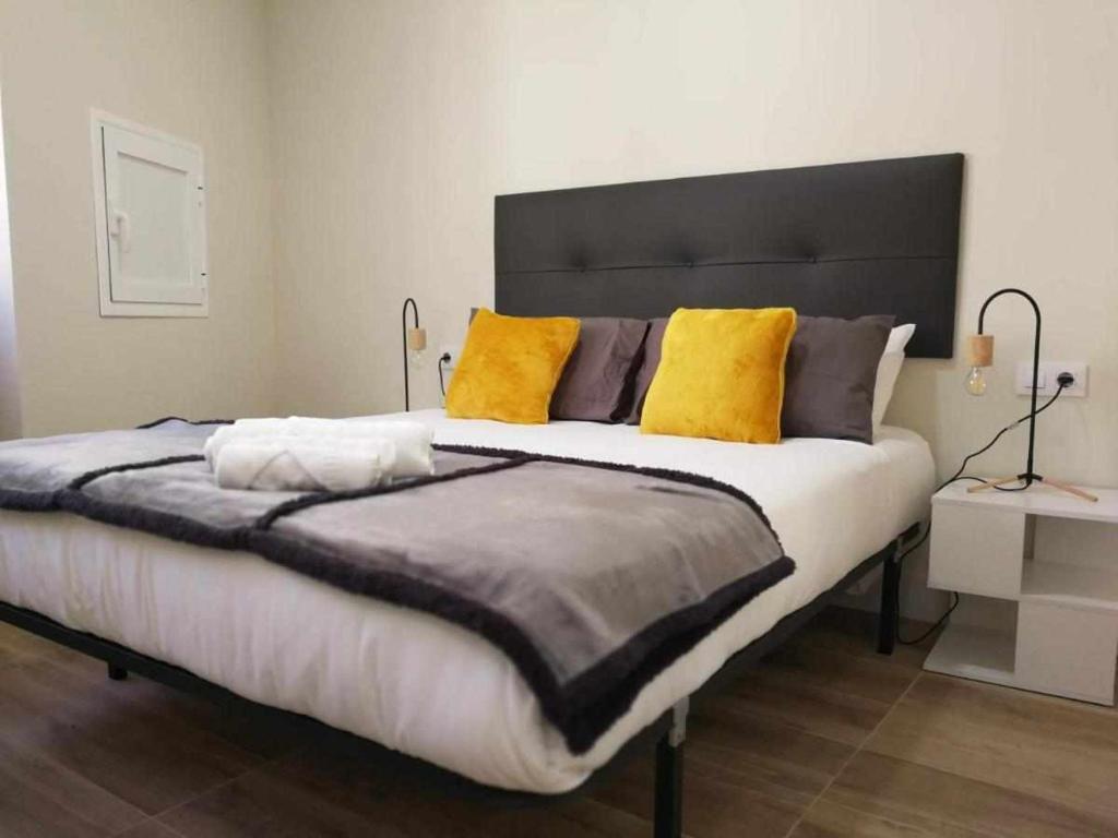 1 dormitorio con 1 cama grande con almohadas amarillas en KubiK APARTAMENTOS K1, en Cáceres
