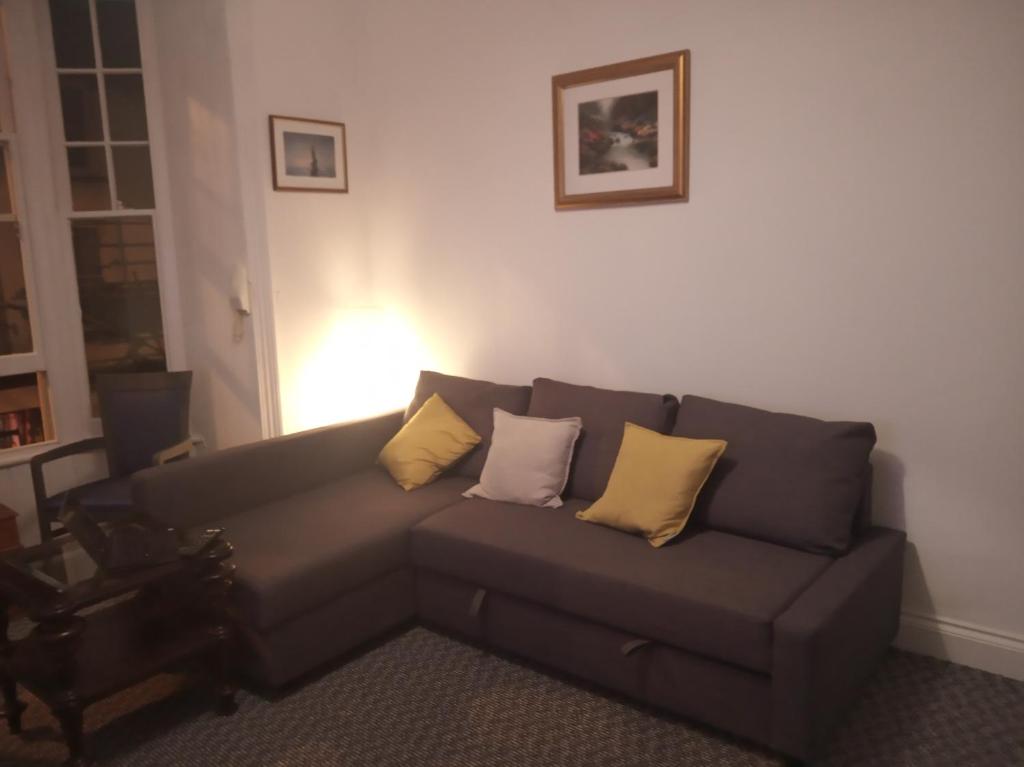 a living room with a gray couch with yellow pillows at Apartment One Aberystwyth Town Centre in Aberystwyth
