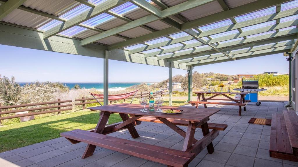 a picnic table on a patio with a view of the ocean at Antonio's Paradise in Culburra Beach