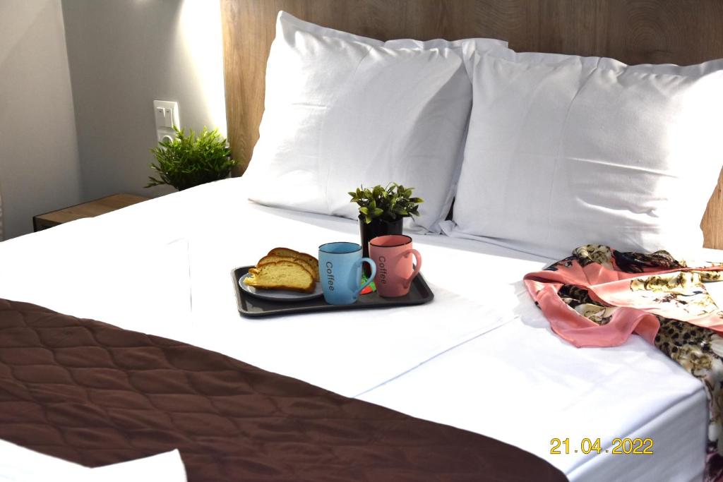 a bed with a tray of food and two cups on it at Le An Apartments Thalassa in Keramotí