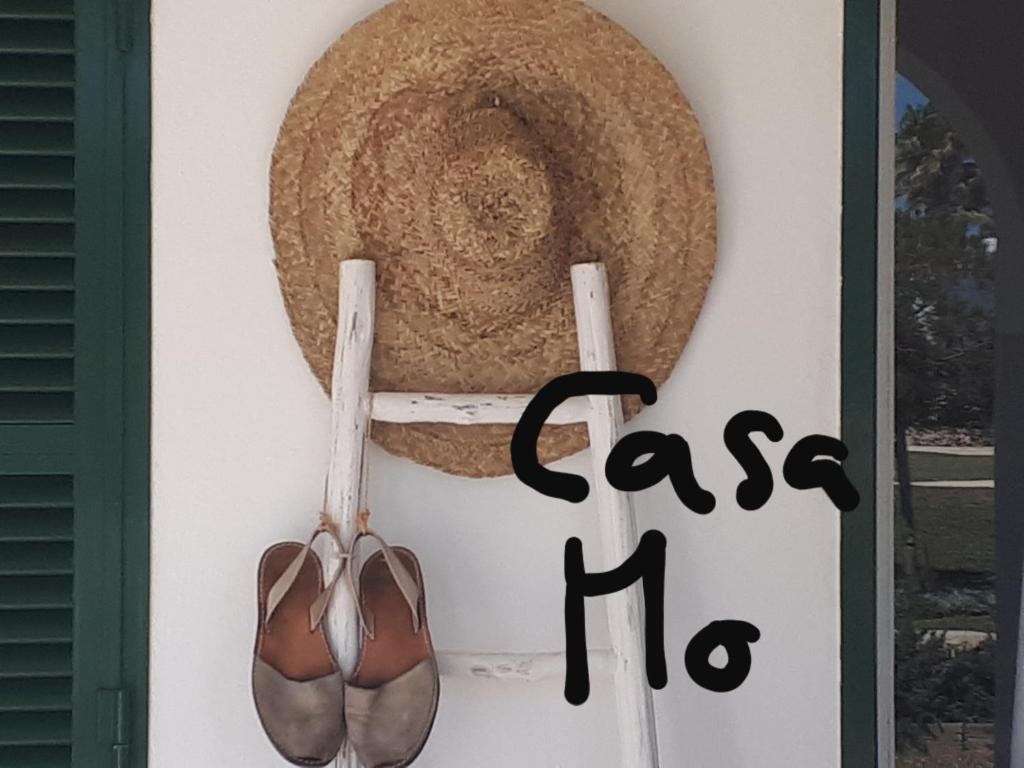 a sign with a hat and shoes on a door at Casa Mo in Cala en Bosc