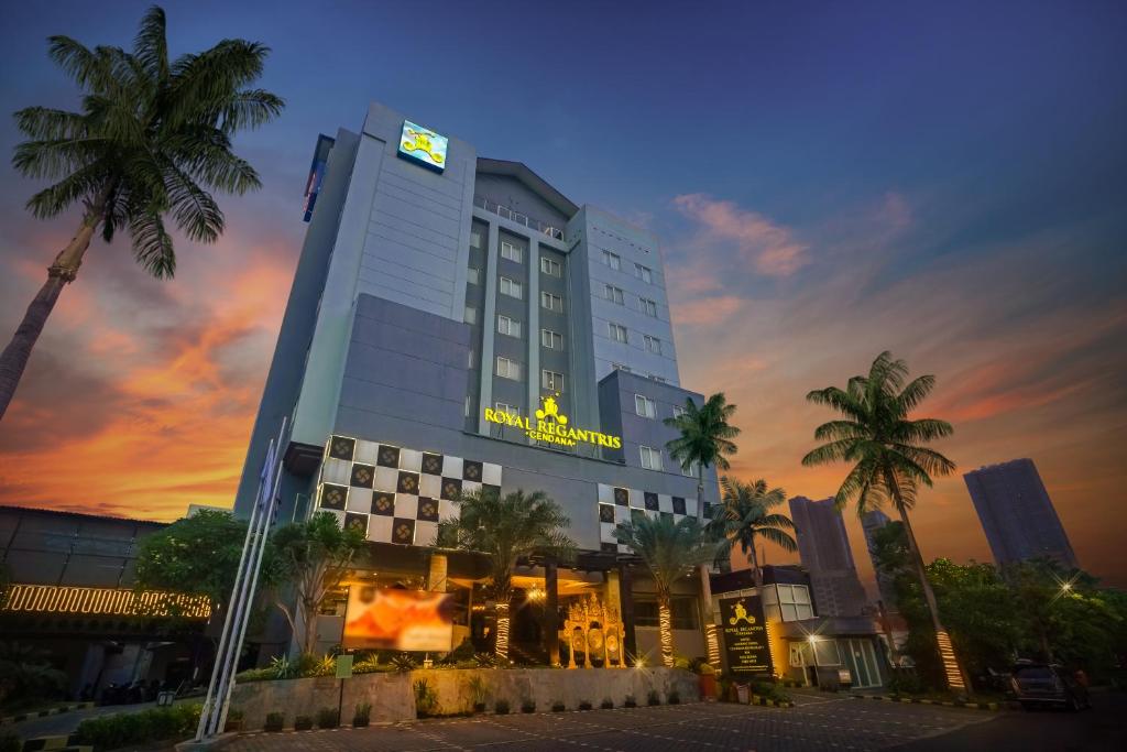 un edificio de hotel con palmeras frente a la puesta de sol en Royal Regantris Cendana Formerly Royal Singosari, en Surabaya