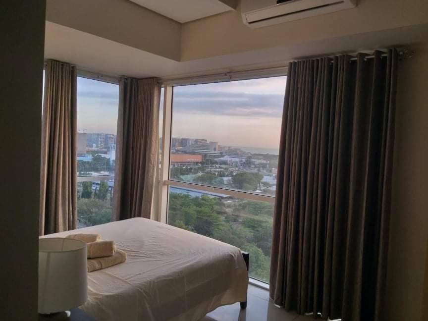 ein Schlafzimmer mit einem Bett und einem großen Fenster in der Unterkunft De Luxe, Standard and Studio Suites -The Breeze Residences-close to Airport,Mall of Asia, US Embassy in Manila