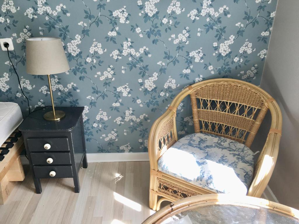 a room with a wicker chair and blue and white wallpaper at Hvidegaard Møn in Stege