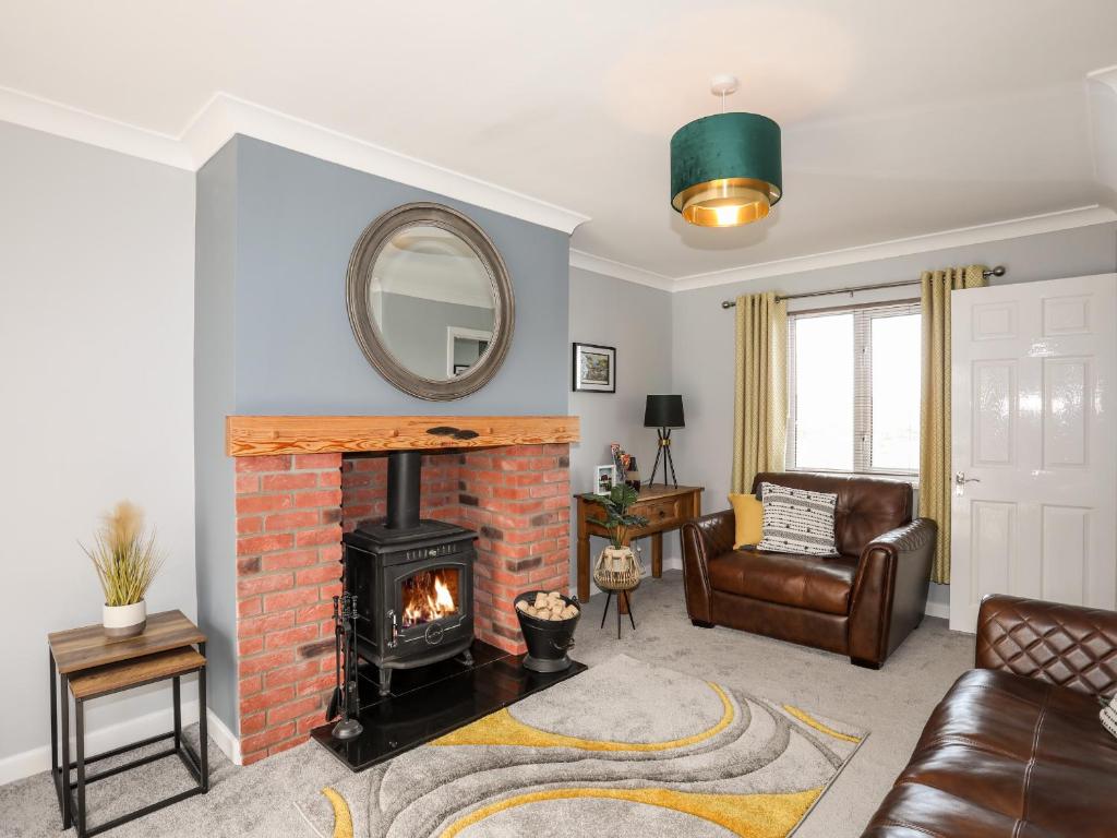 a living room with a brick fireplace and a mirror at Mor a Mynydd in Caernarfon