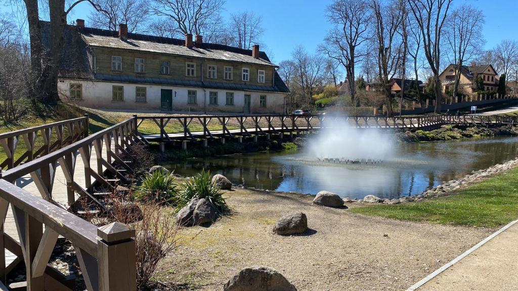a bridge over a river with a fountain in front of a building at Pils Parka Apartamenti in Kuldīga