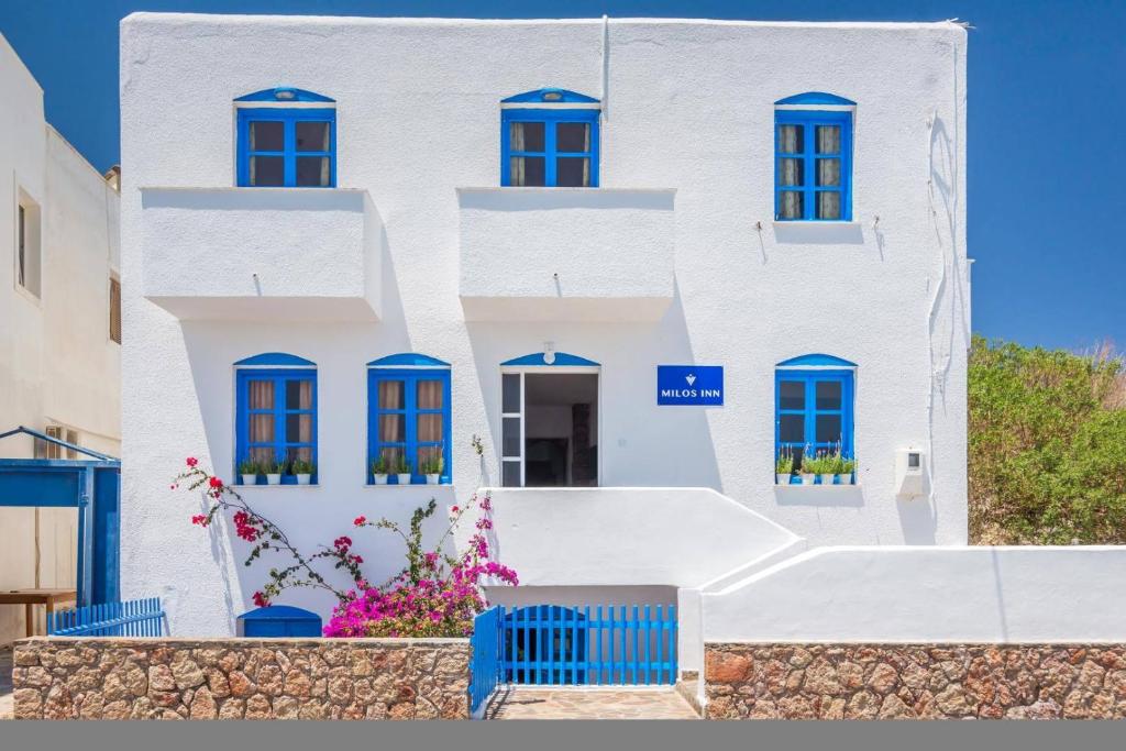 um edifício branco com janelas azuis e flores em Milos Inn em Adamas