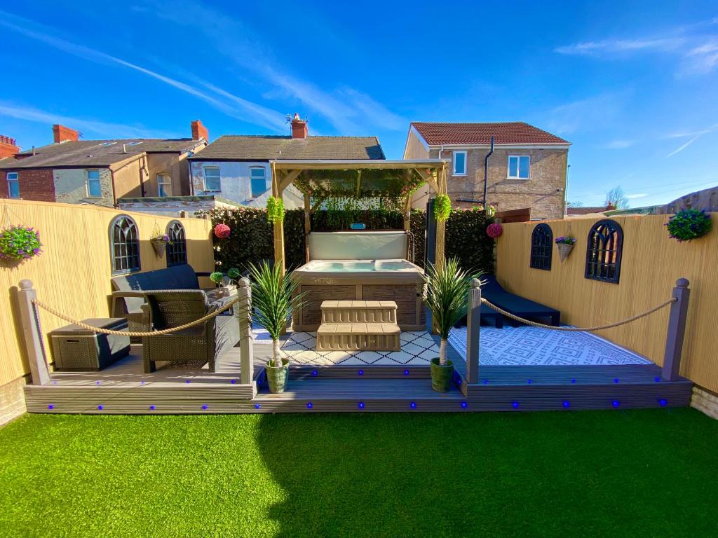 a backyard with a wooden deck and green grass at NEW…THE HOTTUB HOUSE BLACKPOOL PLEASURE BEACH in Blackpool