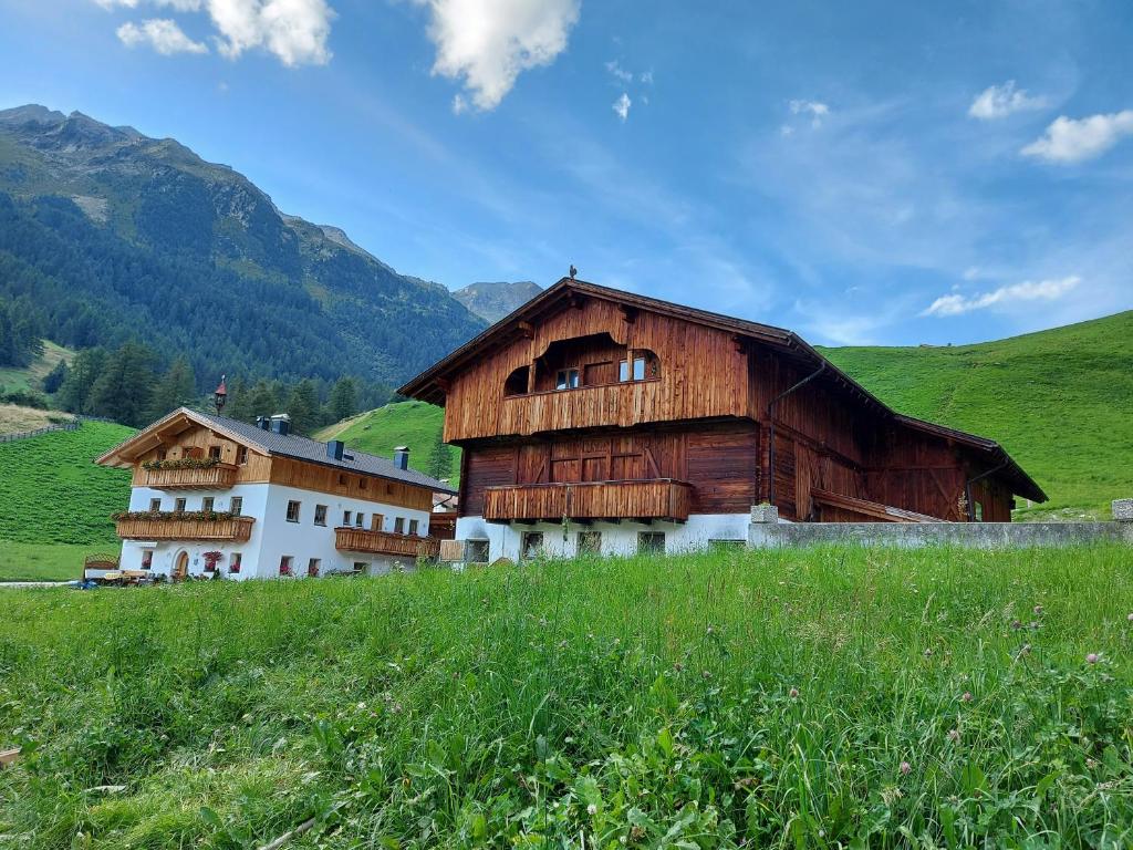 ein großes Holzgebäude auf einem Feld mit einem Berg in der Unterkunft Mooserhof in Sand in Taufers