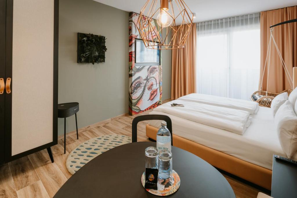 ein Hotelzimmer mit einem Bett und einem Tisch mit Getränken darauf in der Unterkunft Rioca Vienna Posto 2 in Wien