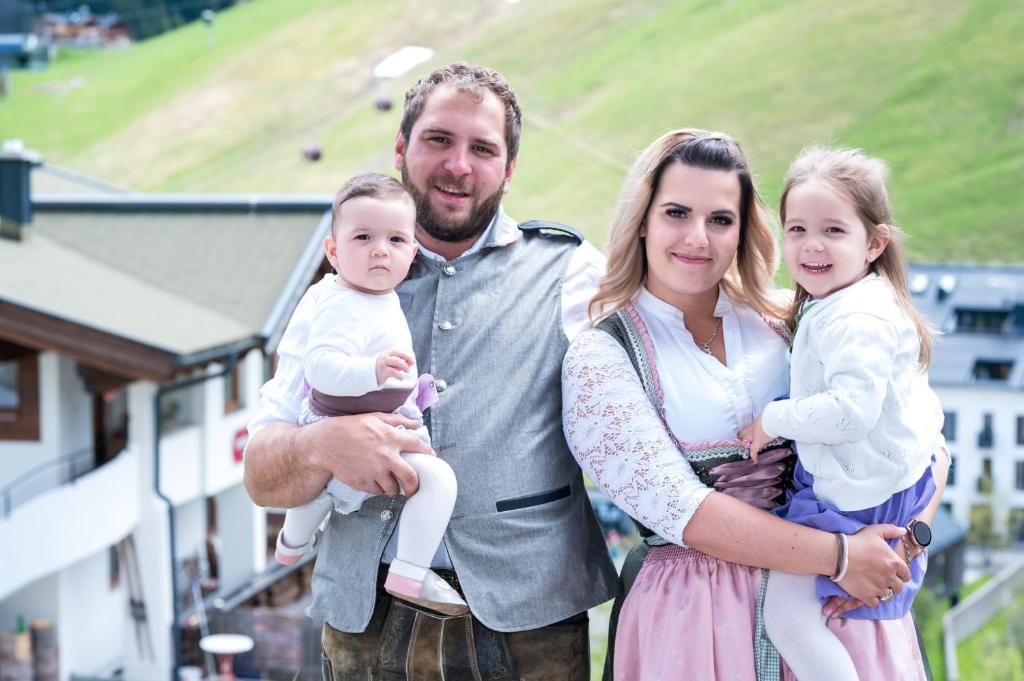 een man en een vrouw die een baby vasthouden bij Landhaus-Pension Pattis in Saalbach Hinterglemm