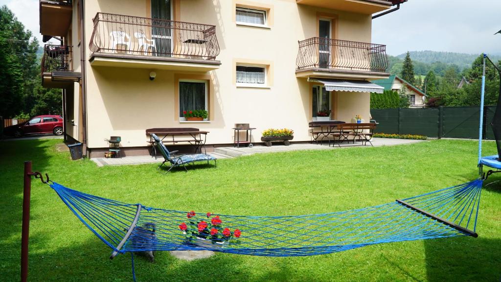 a hammock in a yard in front of a house at Groń pokoje w centrum in Brenna