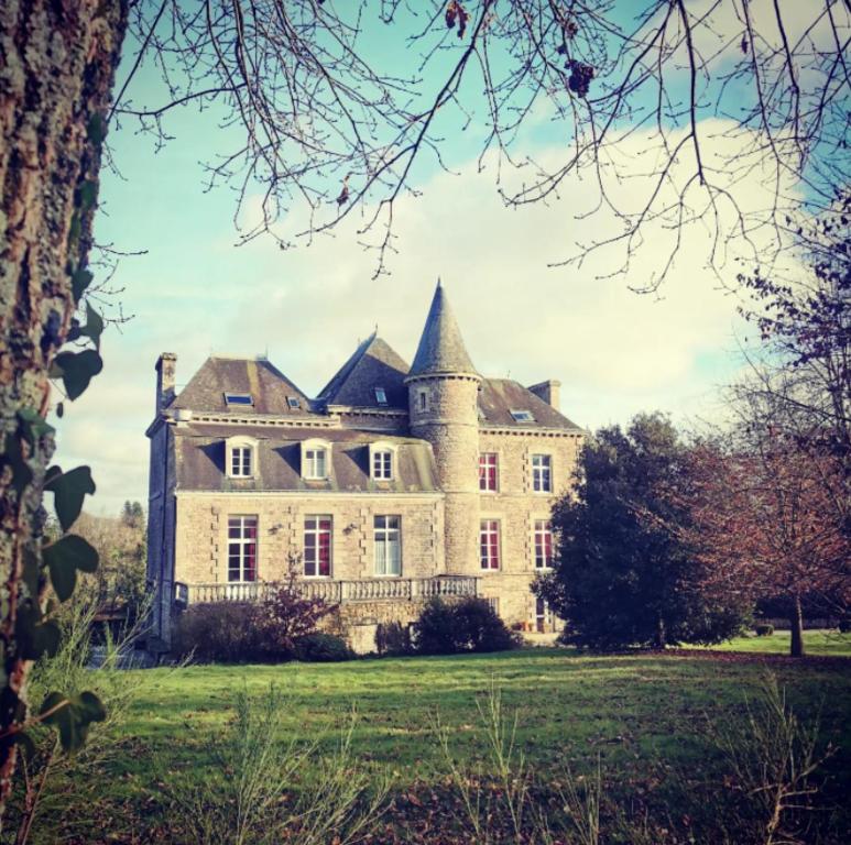 a large stone house on a grass field at Hotel Le Domaine De La Ferriere in Buléon