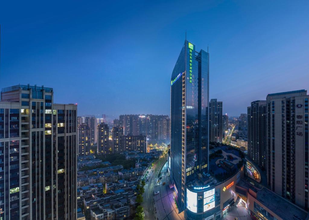 Holiday Inn Express Meishan Dongpo, an IHG Hotel في Meishan: أفق المدينة في الليل مع مبنى طويل