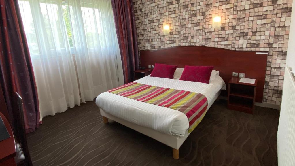 a bedroom with a large bed with red pillows at Hôtel Fontaine Morlaix in Morlaix