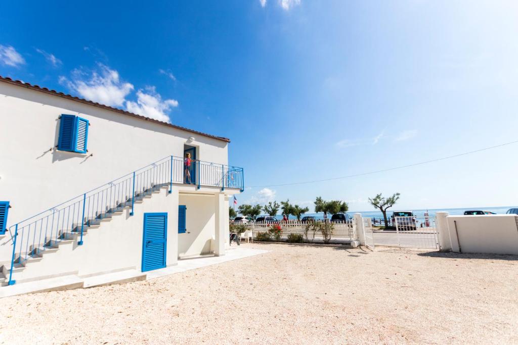 een wit gebouw met blauwe deuren en trappen op het strand bij Casabianca Appartamenti in Numana