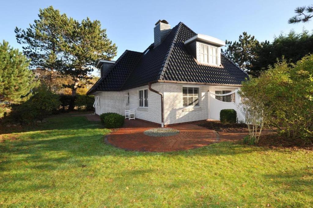 een wit huis met een zwart dak op een tuin bij Ferienhaus Pinewood Villa in Sankt Peter-Ording