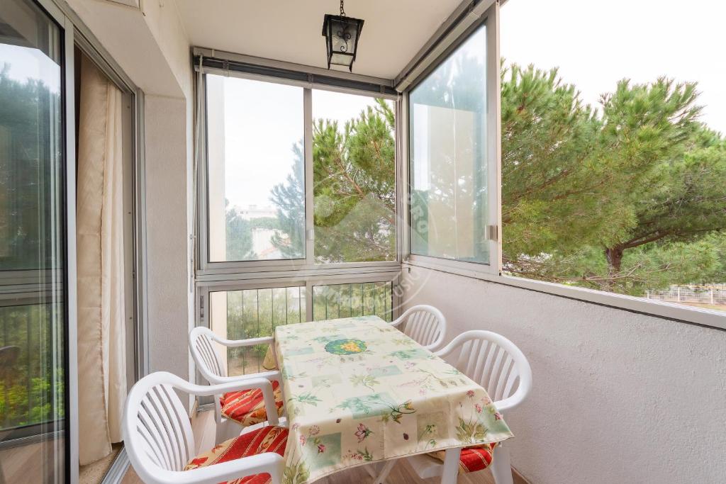 d'une table et de chaises sur un balcon avec fenêtres. dans l'établissement AS20399 - P2 centre ville avec parking privatif dans une résidence à 150m de la plage, au Grau-du-Roi