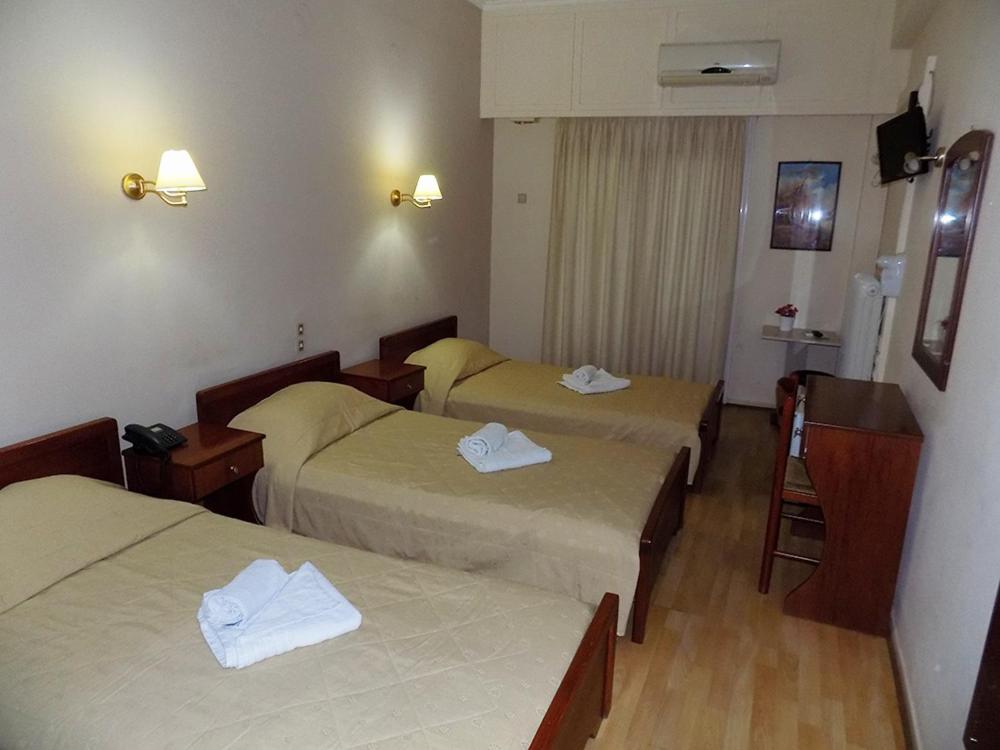 a hotel room with three beds with towels on them at Hotel King Pyrros in Ioannina