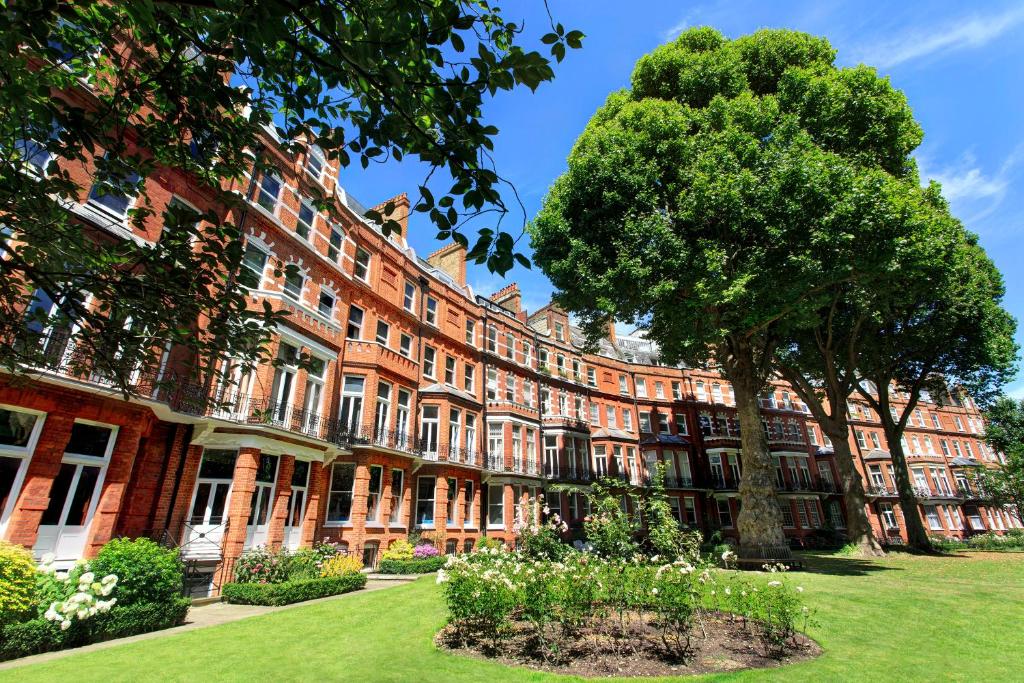 um grande edifício de tijolos vermelhos com uma árvore no quintal em The Franklin London - Starhotels Collezione em Londres