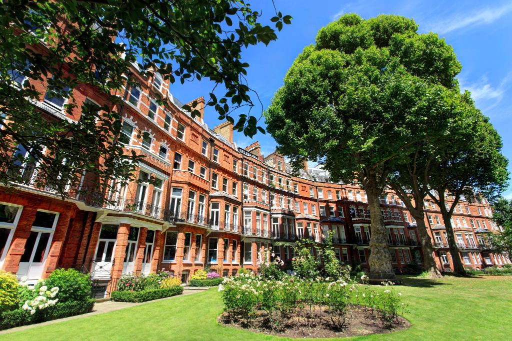 a large red brick building with a tree in the yard at The Franklin London - Starhotels Collezione in London
