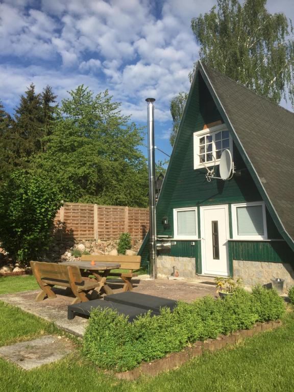 una casa verde con mesa de picnic y banco en Ferienhaus Typ - Finnhütte en Mühl Rosin
