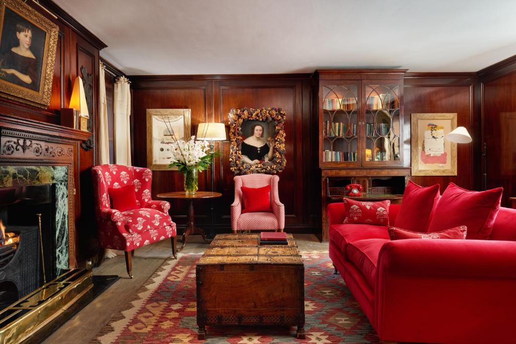 a living room with red furniture and a fireplace at The Pelham London - Starhotels Collezione in London