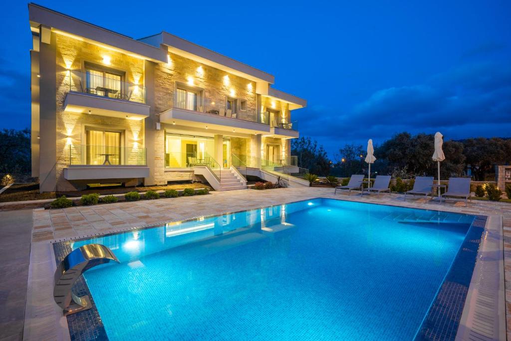 a villa with a swimming pool in front of a house at Supreme Luxury Suites in Skala Potamias