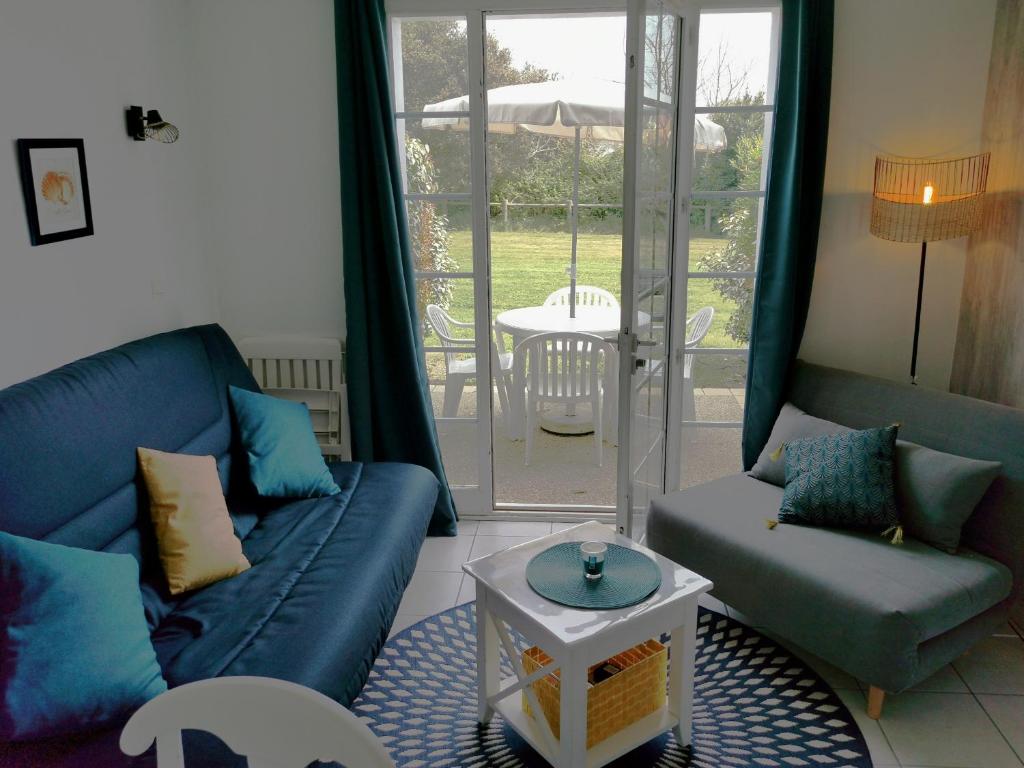 a living room with a couch and a table at Le Bosquito - Piscine Avril a Septembre in Saint-Hilaire-de-Talmont