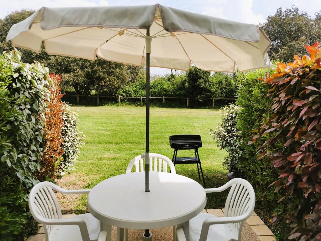 a white table and chairs with an umbrella at Le Bosquito - Piscine Avril a Septembre in Saint-Hilaire-de-Talmont