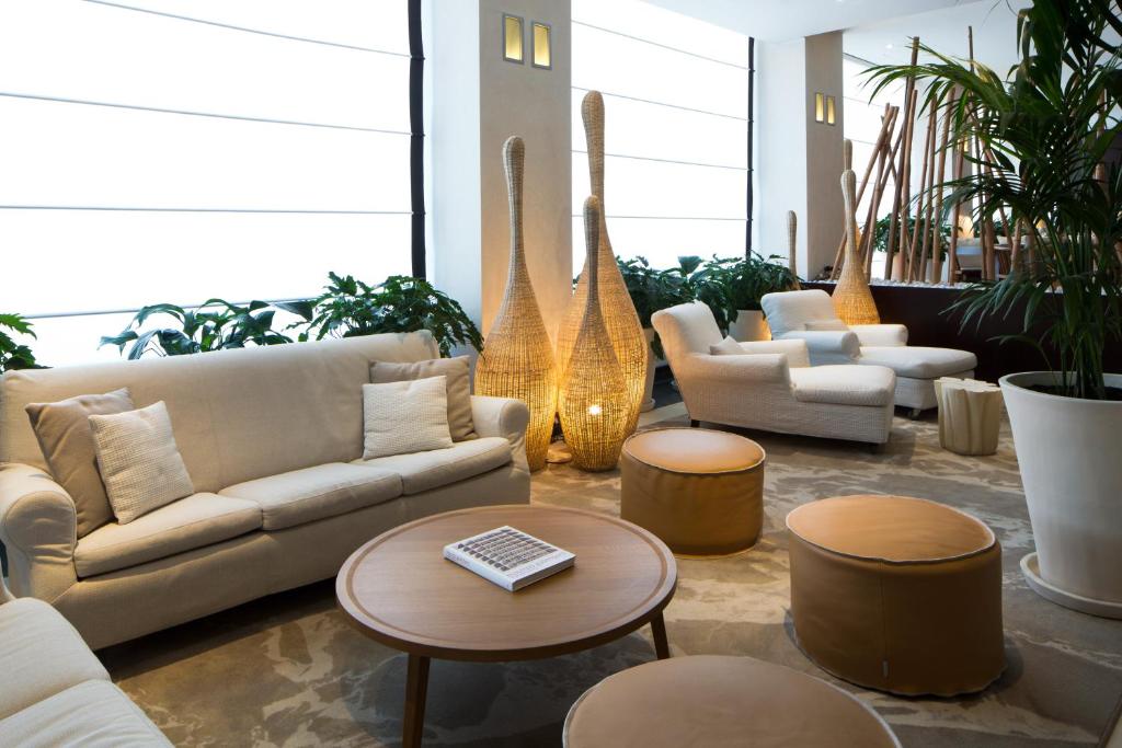 a living room with couches and tables and plants at Starhotels Excelsior in Bologna