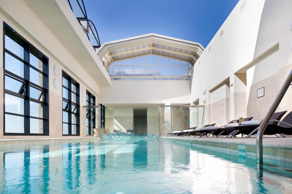 una piscina coperta con sedie in un edificio di Starhotels Grand Milan a Saronno