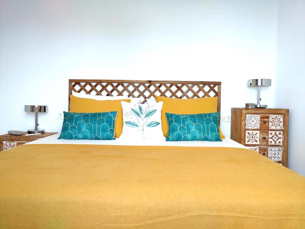 een slaapkamer met een groot bed met gele en blauwe kussens bij Apartment Aqui Todo Empieza - Pool view - Free WiFi - smart TV-Residence Senator in Costa Teguise