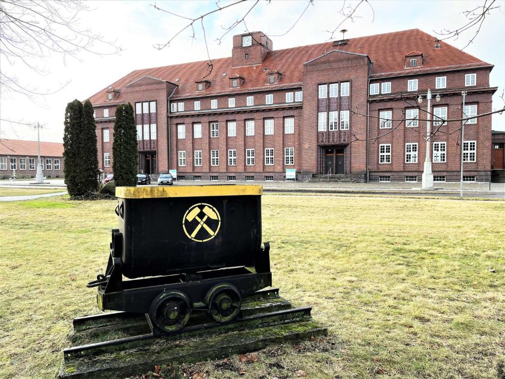 un tren negro sentado en un campo frente a un edificio en IBS Begegnungszentrum, en Laubusch