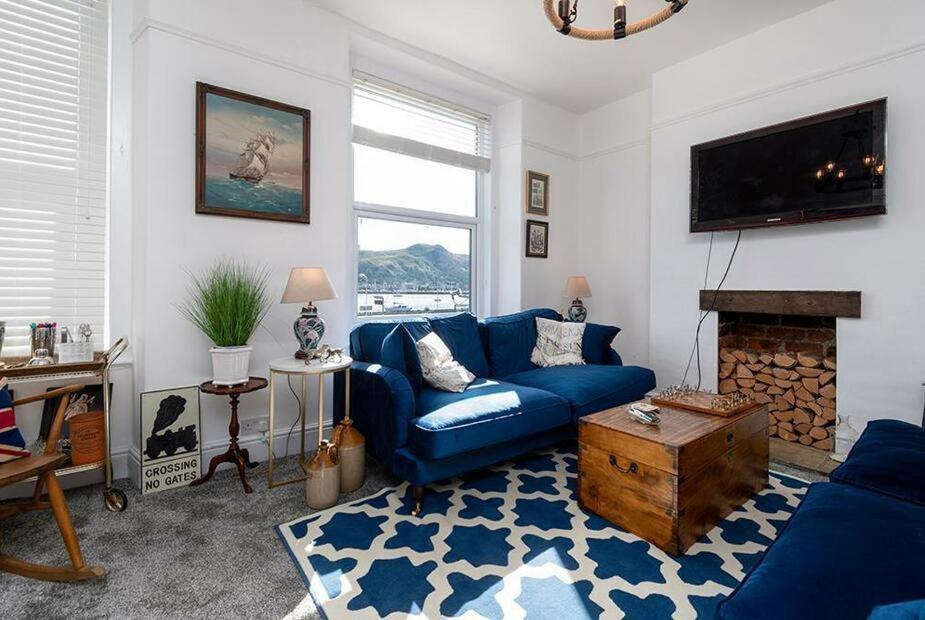 a living room with a blue couch and a fireplace at Haulfryn Apartment in Conwy