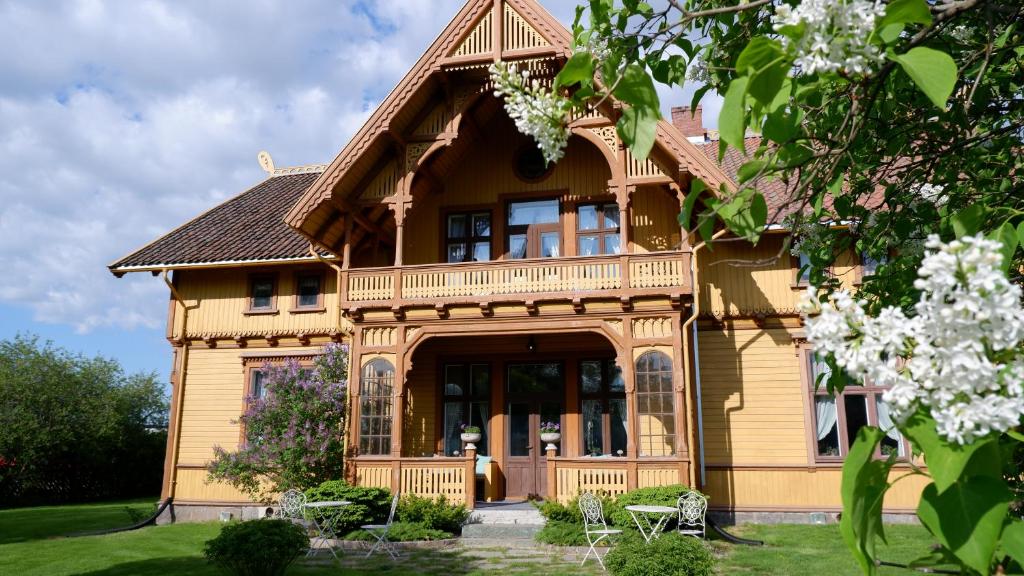 a large yellow house with a balcony on it at Negarden 1897 in Åsnes