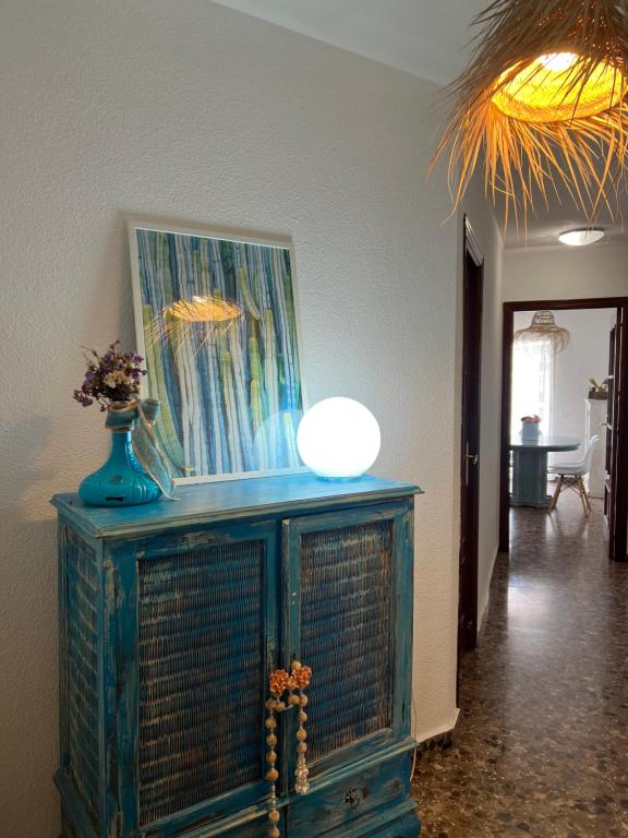 ein blauer Schrank mit einem Gemälde und einer Vase darauf in der Unterkunft Apartamento con Vistas al Mar 1ºA in Benidorm