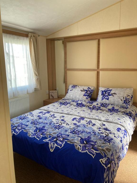 a bedroom with a bed with blue flowers on it at Caravan Skegness GB 148 in Chapel Saint Leonards