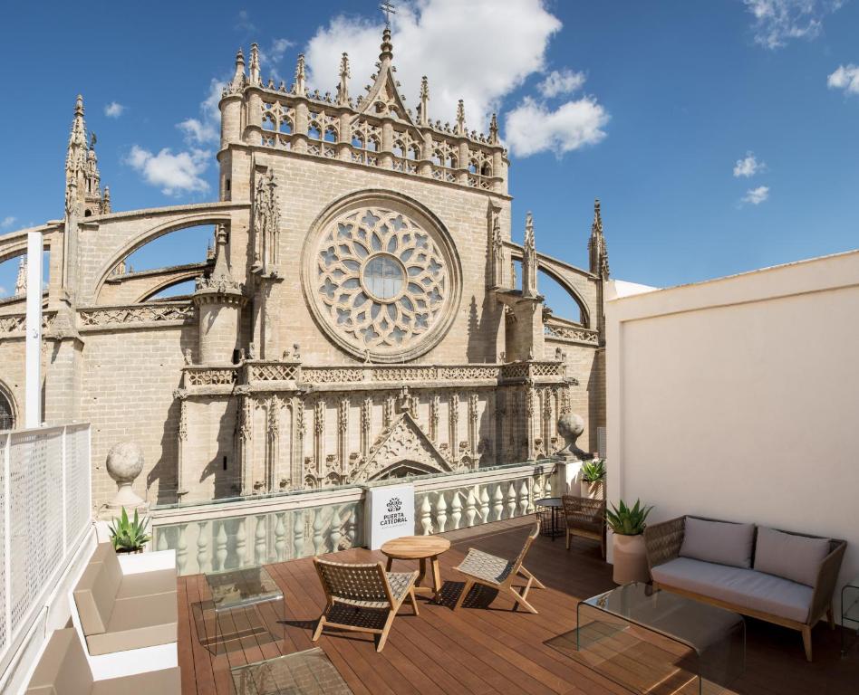 uma varanda com cadeiras e um edifício com uma torre do relógio em Puerta Catedral Suites em Sevilha