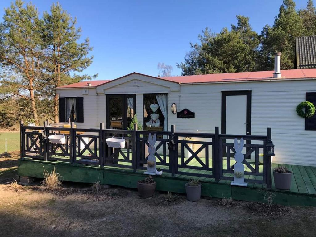 une petite maison blanche avec une terrasse couverte et une clôture dans l'établissement Leśna cisza w Ładnówku, à Kruszyny Szlacheckie