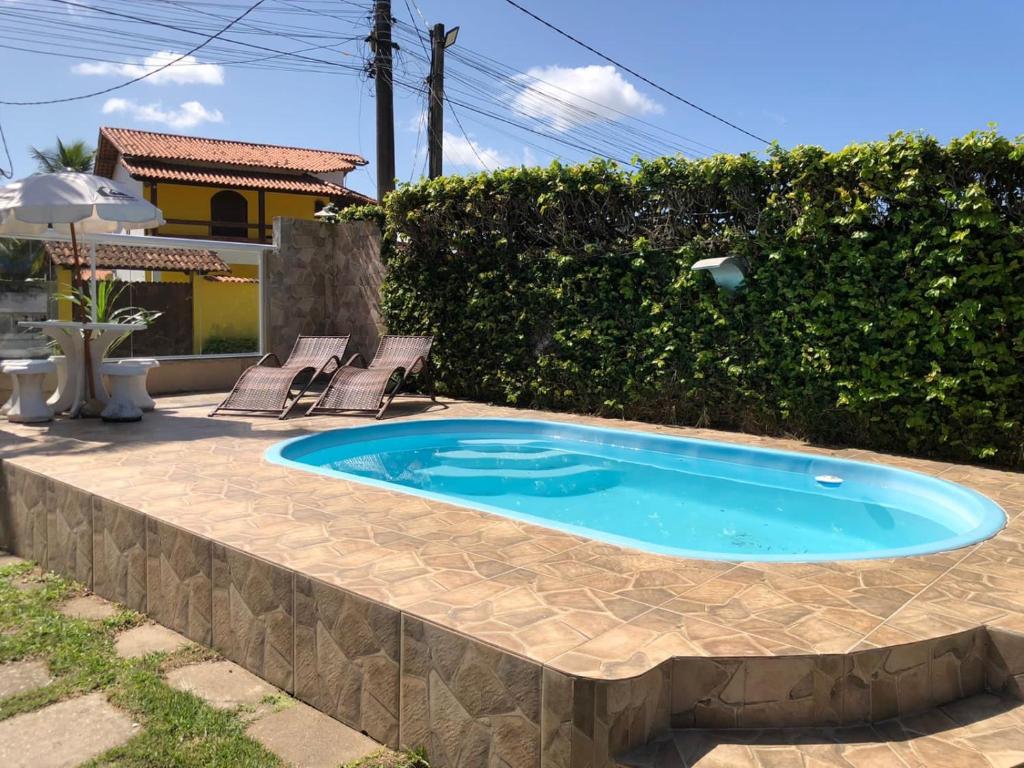 a small swimming pool with two chairs in a backyard at Pousada do Suiço in Saquarema